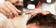 Ein Mann bekommt die Haare kurz geschnitten, die Hände des Friseurs über der Stirn