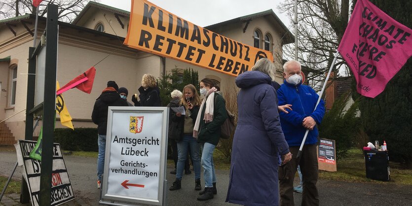 Klimaaktivist Henning Jeschke und UnterstützerInnen vor dem Lübecker Amtsgericht mit Bannern