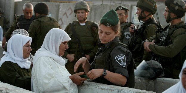 Zwei palästinensische Frauen zeigen einer israelischen Grenzpolizistin ihre Pässe