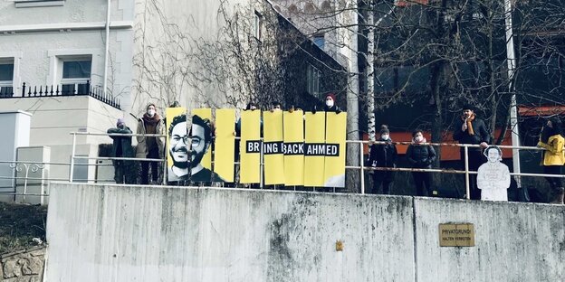 Personen halten ein Plakat hoch mit der Aufschrift "Bring back Ahmed"