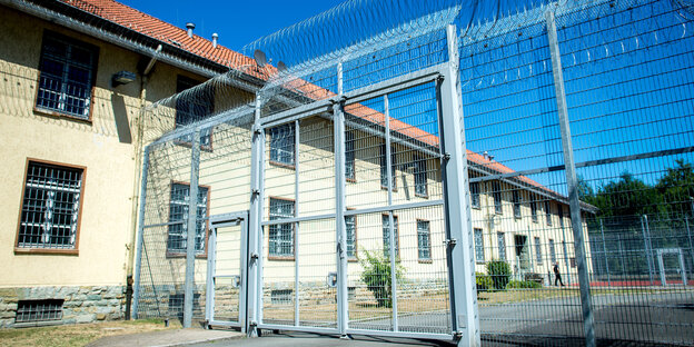 Die Abteilung für Abschiebehaft in Langenhagen. Ein zweistöckiges langes Gebäude steht hinter einem hohen Zaun mit Stacheldraht