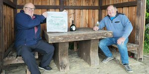 Zwei Männer sitzen bei einem Glas Wein auf einer Bank