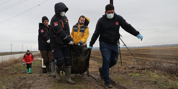 Männer ziehen auf einem Karren die Leichen der erfrorenen Migranten