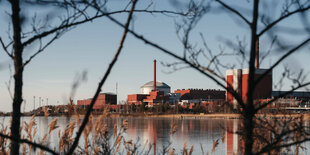 Blick durch Bäume über einen See auf Atomkraftwerk Olkiluoto