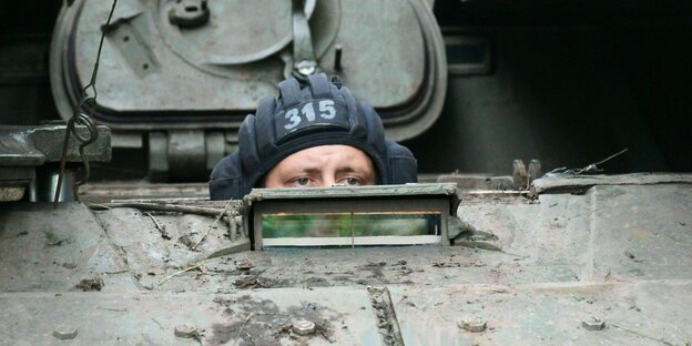 Ein Soldat in Tarnfleck lugt aus der Lucke eines Panzers