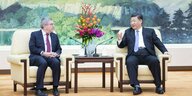Thomas Bach und Xi Jinping sitzen neben einem Tisch, zwischen ihnen ein Blumenstrauß