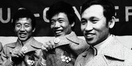 Drei chinesische Sportler zeigen lachend ihre "I love Ney York"-Buttons