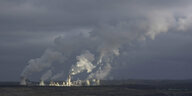Rauch steigt ausd den Schornsteinen eines Kohlekraftwerks auf, düsterer Himmel