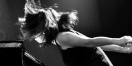 Die Piantistin Aki Takase im Profil: Sie ist im Sprung über ein Piano gebäugt, ihre Haare fliegen durch die Luft und verdecken ihr Gesicht