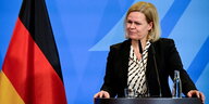 Bundesinnenministerin Nancy Faeser an einem Rednerpult vor einer Deutschland-Flagge