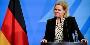 Bundesinnenministerin Nancy Faeser an einem Rednerpult vor einer Deutschland-Flagge