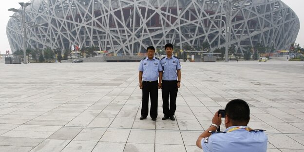Chinesische Polizisten fotografieren sich gegenseitig vor dem Olympiastadion in Peking, das auch Vogelnest genannt wird