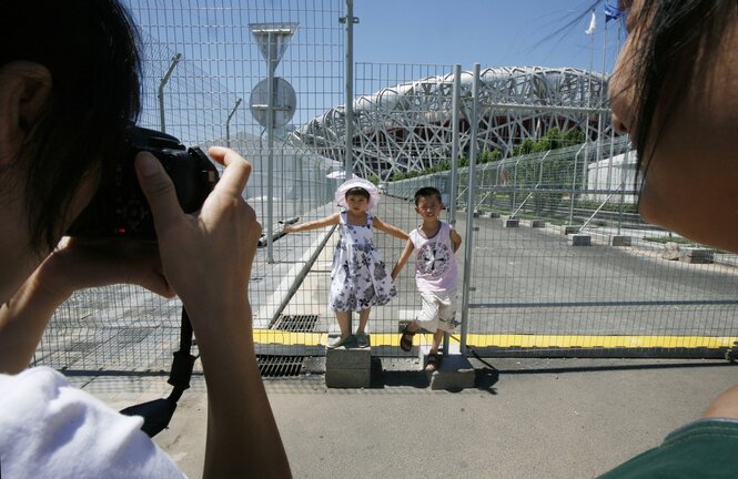 Zwei Kinder werden vor einem Zaun fotografiert