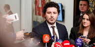 Dritan Abazovic trägt Anzug und Krawatte und steht vor Reportern