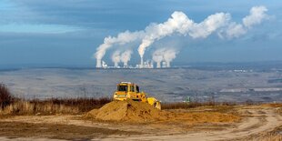 Landschaftsaufnahme mit Braunkohletagebau und rauchenden SChornsteinen eines Kohlekraftwerks