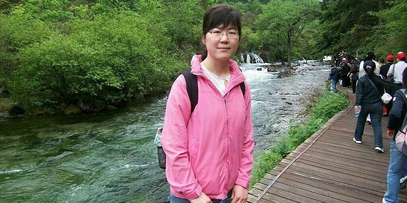 Frau in Wanderkleidung vor einem Fluss und Berg.