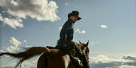 Ein Mann reitet auf einem Pferd und trägt einen Cowboyhut