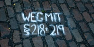 "Weg mit Paragraph 218 und 219" ist auf ein Straßenpflaster geschrieben