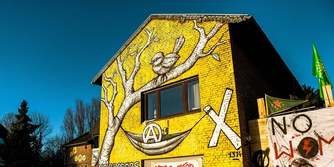 Die Fassdae eines Hauses ist mit einem Baum vor gelbem Hintergrund bemalt