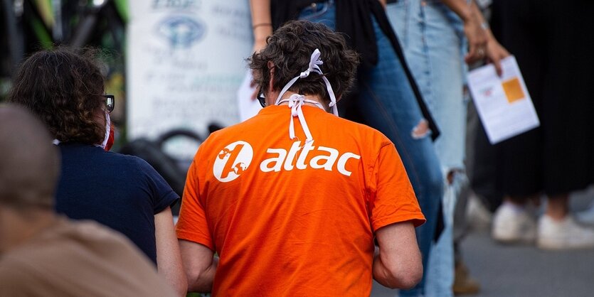 Ein mann trägt ein T-shirt mit dem LOGO von Attac