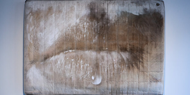 Eine bemalte Matratze: Das Gemälde einer Mundpartie zeigt LIppen, die von einem Wassertrofpen benetzt sind