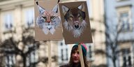 Eine Frau mit Plakaten, auf denen ein Luchs und ein Wolf abgebildet sind