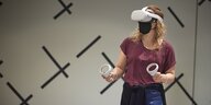 Eine Frau bewegt sich im Raum mit einem technischen Gerät auf den Kopf und an den Händen