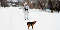 Ein Soldat in weißem Tarnanzug und ein Hund in SChneelandschaft