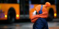 Eine Frau trägt eine orangefarbene Wollmütze und einen orangefarbenen Schal
