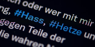 Auf dem Bildschirm eines Smartphones sieht man die Hashtags Hass und Hetze in einem Twitter-Post.