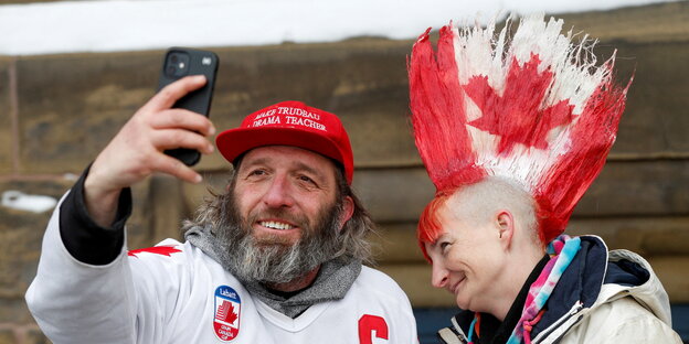 Eine Frau hat einen kunstvollen Haarschopf mit kanadischer Flagge und ein Mann macht ein Selfie von Beiden