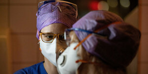 Zwei Pflegerinnen der intensivstation schauen sich an, sie tragen Masken