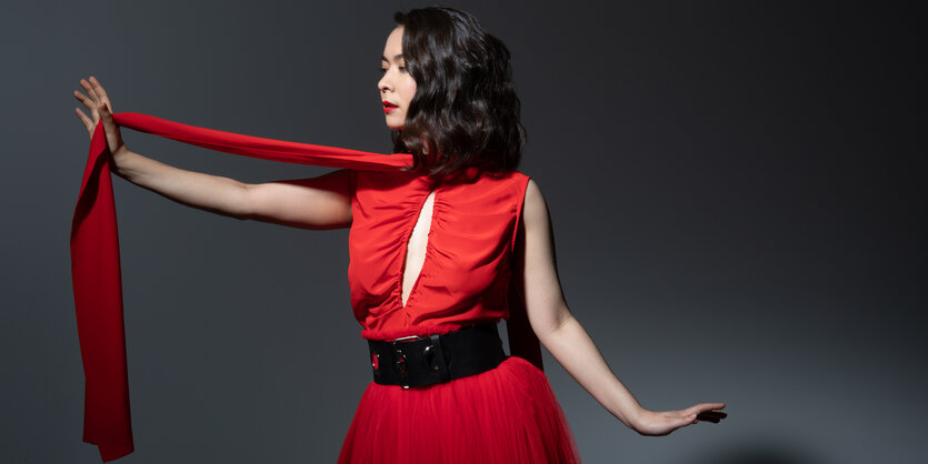 Mitski in leuchtend rotem Kleid und ebensolchem Schlipps