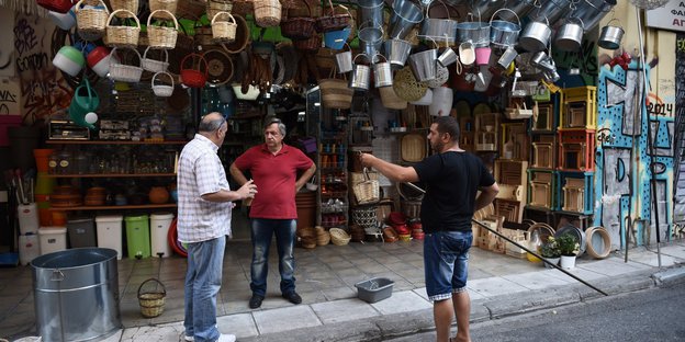 Drei Männer stehen vor einem Geschäft in Athen
