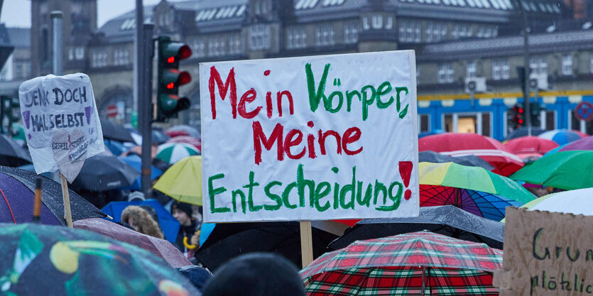 Ein Teilnehmer einer Demonstration von Corona-Impfgegnern auf dem Glockengießerwall hält ein Transparent mit den Aufschrift „Mein Körper, meine Entscheidung!“.