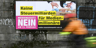 Ein Fahradfahrer fährt an einem Wahlplakat vorbei.