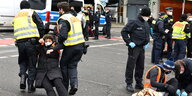 Demonstrierende werden von der Polizei weggetragen, da sie eine Straße blockierten