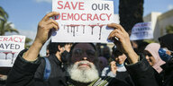 Ein Mann hält ein Plakat mit der Aufschrift "Save our Democracy" hoch