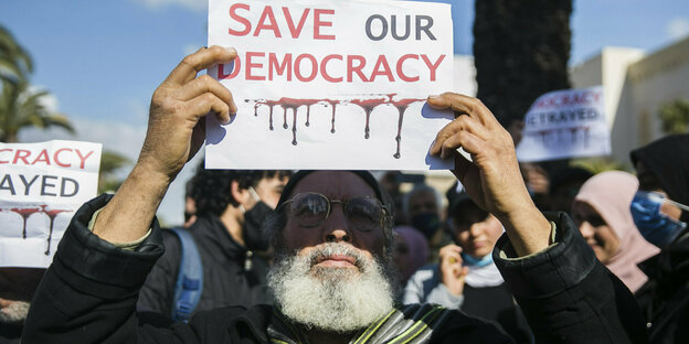 Ein Mann hält ein Plakat mit der Aufschrift "Save our Democracy" hoch