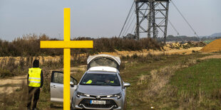 Ein gelbes Holzkreuz in der Landschaft.