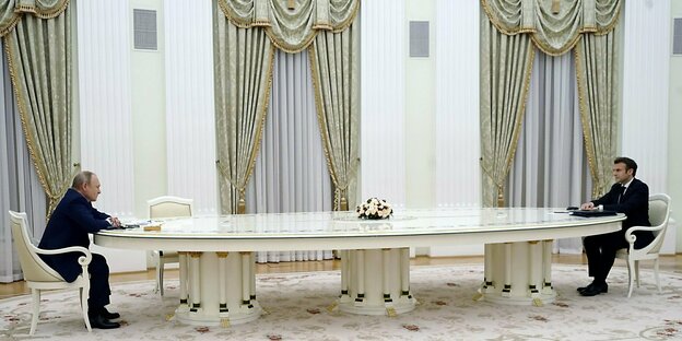 Putin und Macron sitzen an den Ende eines sehr großen Tisches weit auseinander