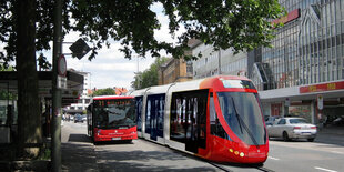 Eine Straßenbahn neben einem Bus unter Bäumen