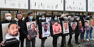 Angehörige der Opfer halten Bilder der Opfer vor dem hessischen Landtag während einer Mahnwache