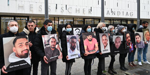 Angehörige der Opfer halten Bilder der Opfer vor dem hessischen Landtag während einer Mahnwache