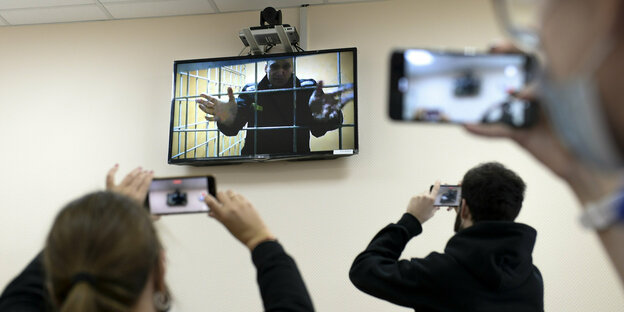 Menschen filmen mit Handys einen Bildschirm, auf dem Alexej Nawalny zu sehen ist