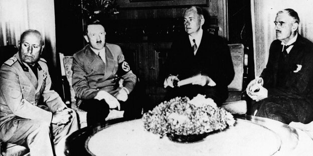 Mussolini, Hitler, Chamberlain und eine andere Person an einem Tisch