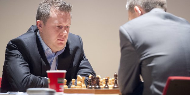 Arkadij Naiditsch sitzt am Schachbrett einem Gegner gegenüber