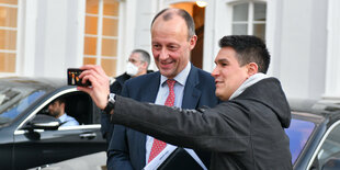 Friedich Merz macht mit einem Anhänger einen Selfie.