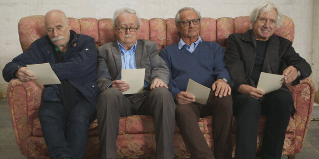Vier ältere Männer sitzen mit Zetteln in der Hand auf einem Sofa