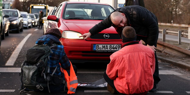 Ein Autofahrer Diskutiert mit Protestierenden.